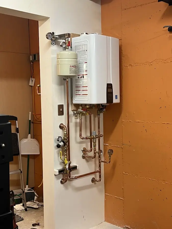 Plumbing technician inspecting water heater connections in Little Canada